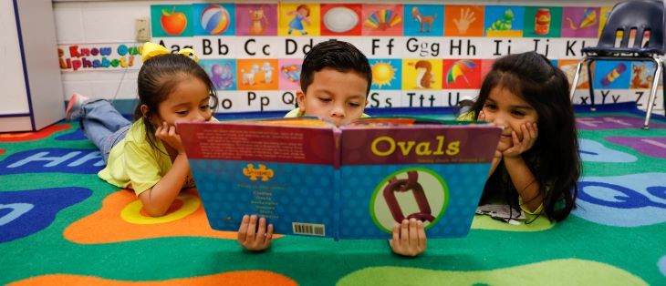 Three students read a book together