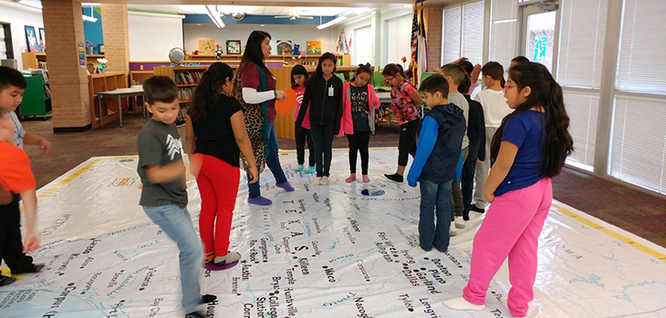 students standing on a map of texas